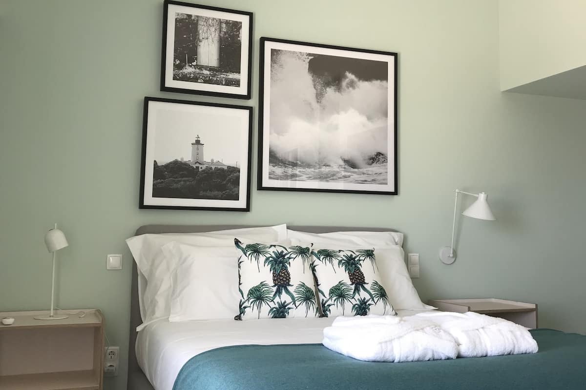 A bedroom with a bed, a nightstand, a lamp, and three framed pictures on the wall.
