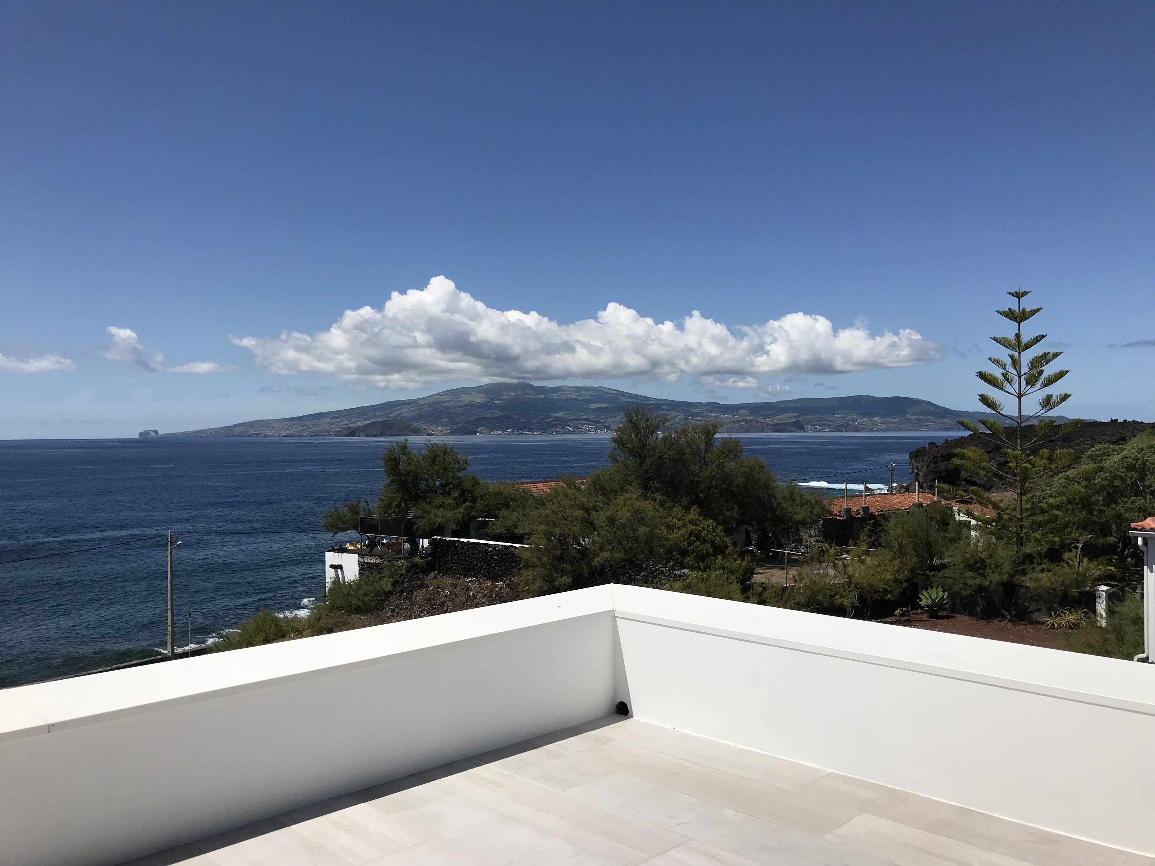Un balcón con vista al mar y montañas a lo lejos.