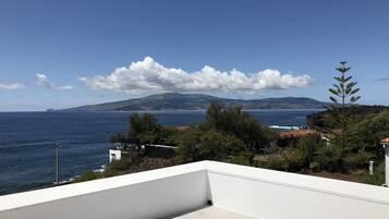 Un balcón con vista al mar y montañas a lo lejos.