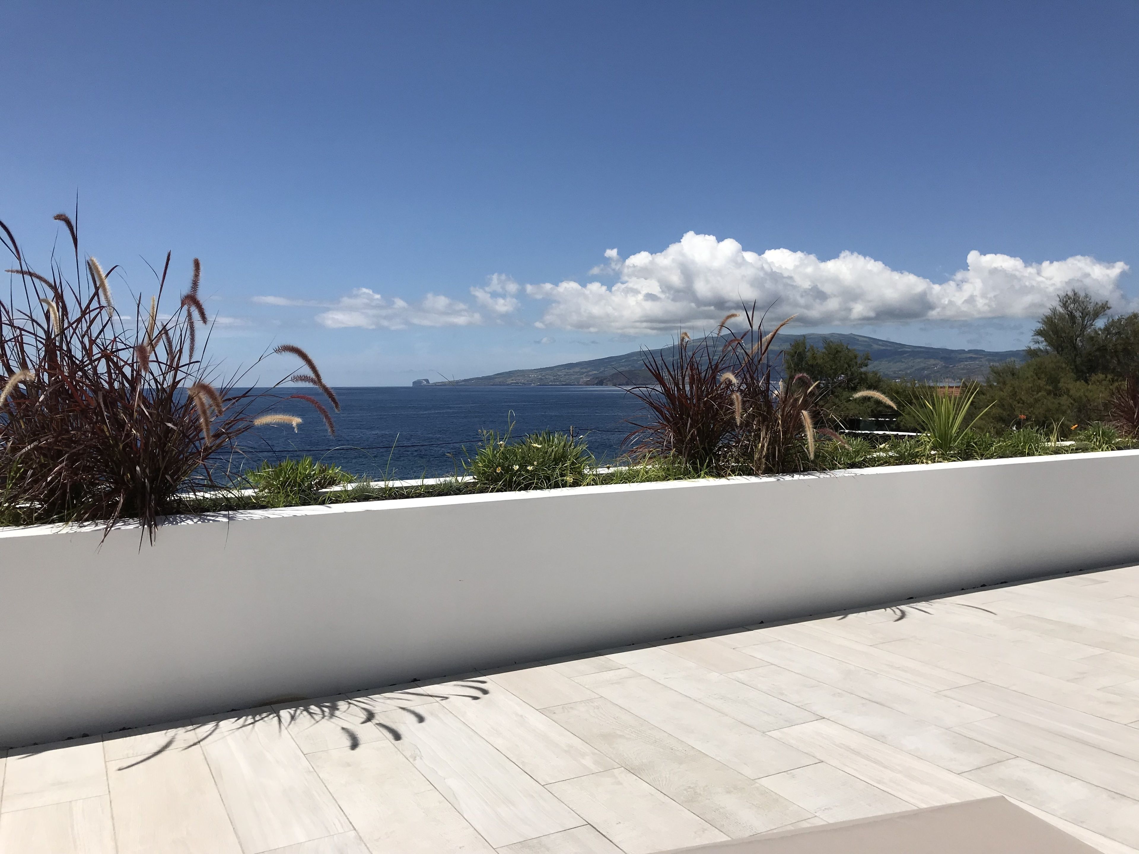 Une terrasse offrant une vue sur la mer et les montagnes lointaines.