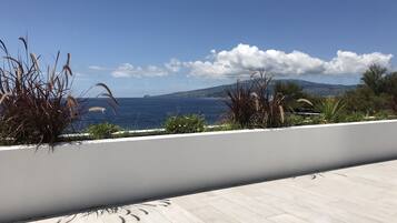 A terrace with a view of the sea and distant mountains.