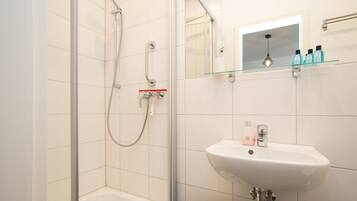 A modern bathroom with a glass shower enclosure, a white sink, and a mirror above the sink.