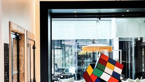 Moderni aula, jossa on suuri ikkuna, värikäs geometrinen veistos ja vastaanottotiski.