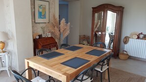 Un área de comedor con una mesa de madera, sillas negras, un mueble de madera y un cuadro en la pared.