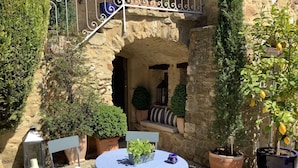 A round table with a blue tablecloth, surrounded by potted plants and a chair. - Maison d'hôtes La Cour des Lauriers (Saint-Hippolyte-de-Montaigu)