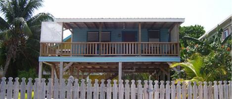 Een huis met twee verdiepingen en een balkon, omringd door een witte picket fence.