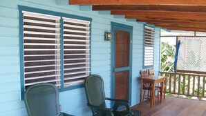 A porch with two green chairs and a wooden table. - Carolyns Other House (Caye Caulker)