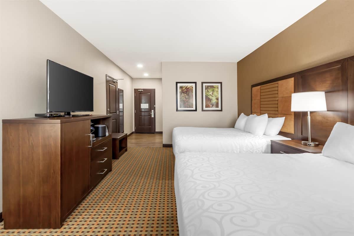 A hotel room with a large bed, a TV, a desk, and a wardrobe.