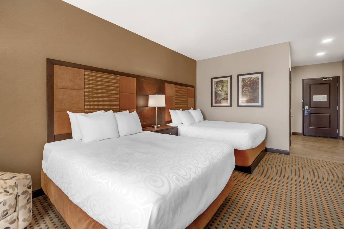 A hotel room with a large bed, two bedside tables, a lamp, and two framed pictures on the wall.