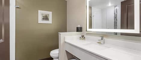 Un baño moderno con lavamanos blanco, un espejo grande y un inodoro.