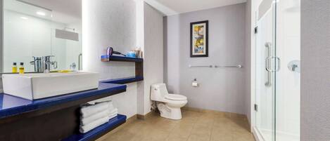 A modern bathroom with a white toilet, a large mirror, and a blue countertop with a sink and towel rack.