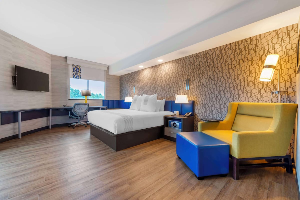 Una habitación de hotel moderna con una cama grande, un escritorio, una silla y un televisor.
