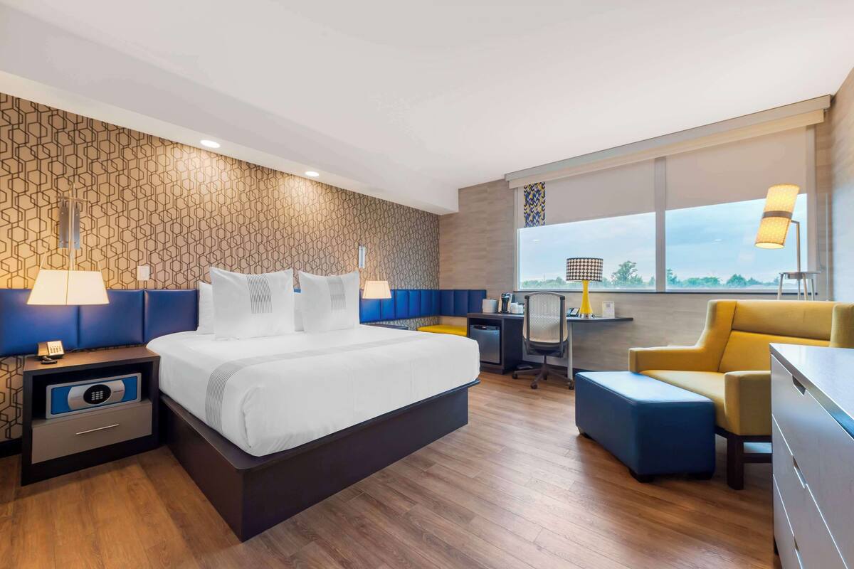 Una habitación de hotel moderna con una cama grande, un escritorio, una silla y un sofá.