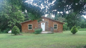 A wooden cabin with a front porch, surrounded by a grassy yard and trees. - Cedar Cabin Located on a Buffalo Farm Near the Buffalo National River (Marshall)