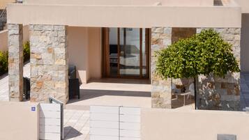 Un edificio moderno con facciata in pietra, ingresso con porta in vetro e un piccolo patio con tavolo e sedie.