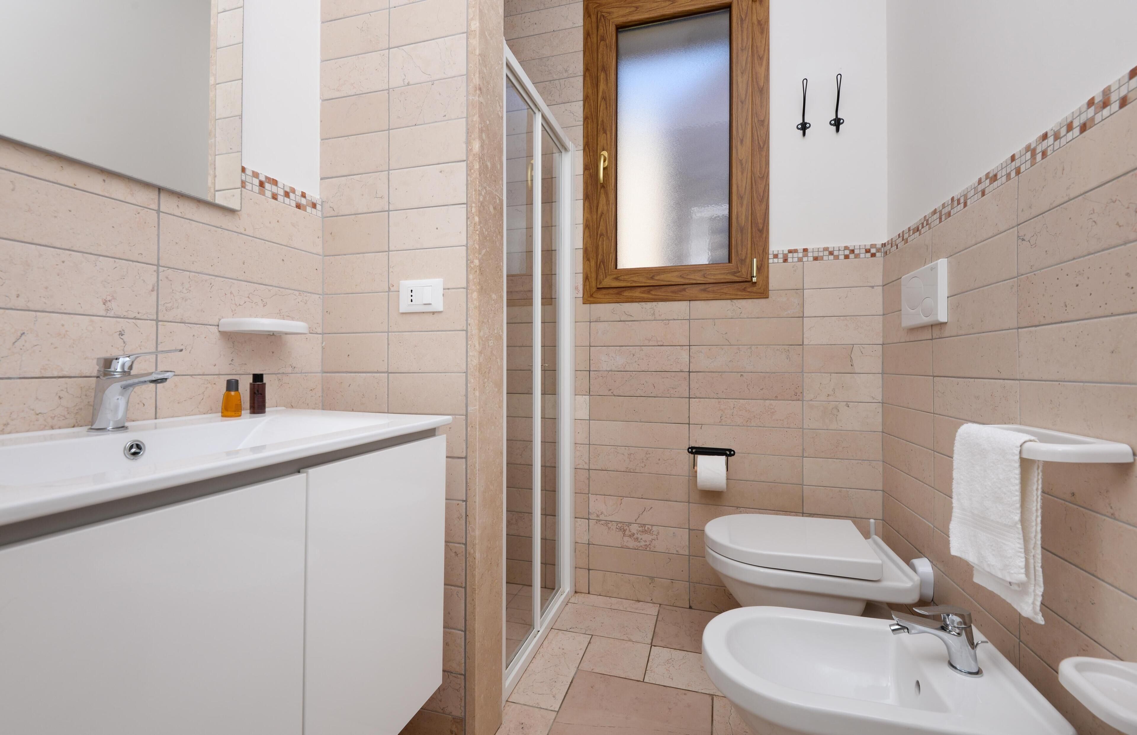 A modern bathroom with a shower, toilet, and sink.