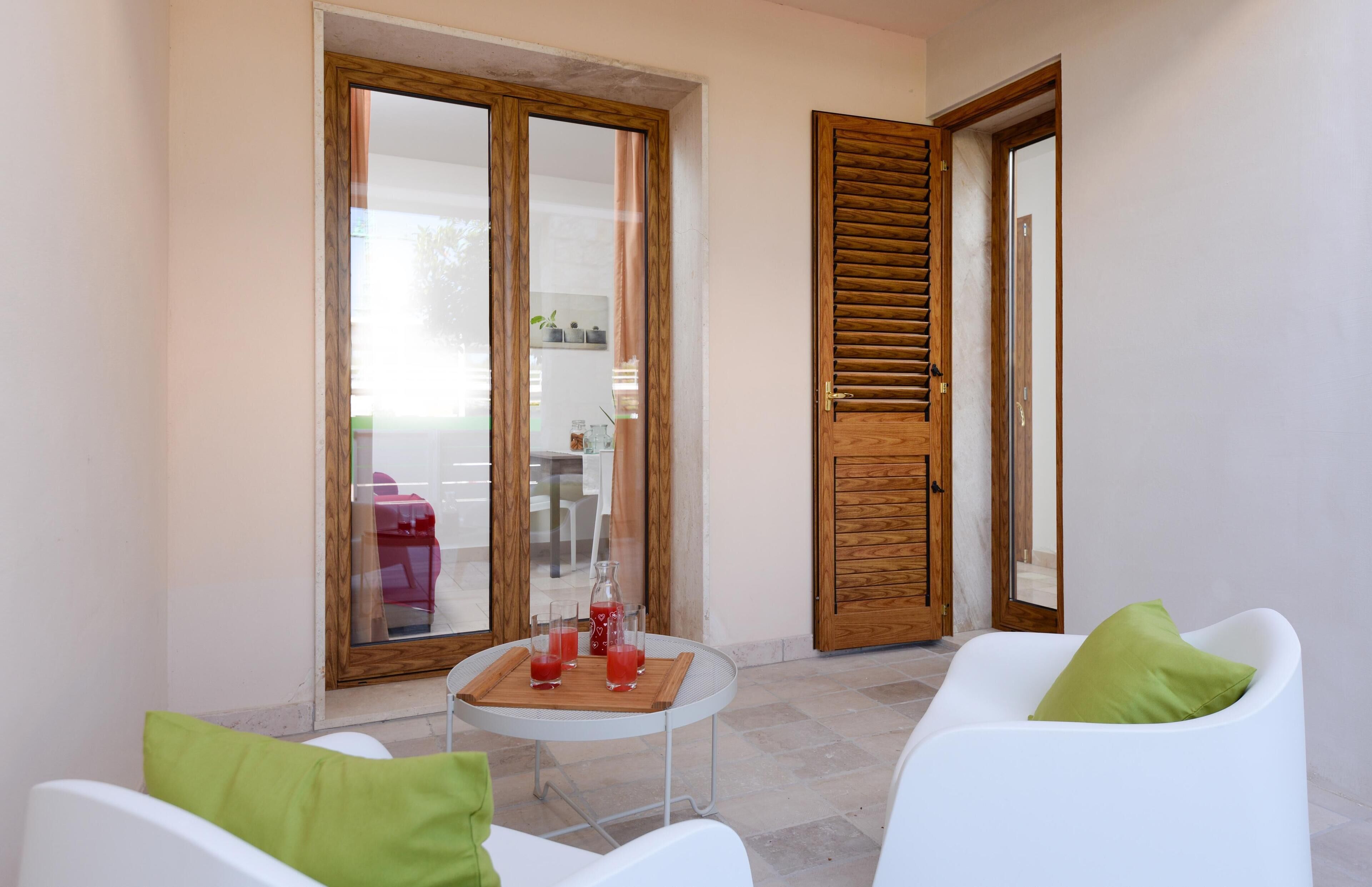 A small patio area with a table, two white chairs, and a wooden door.