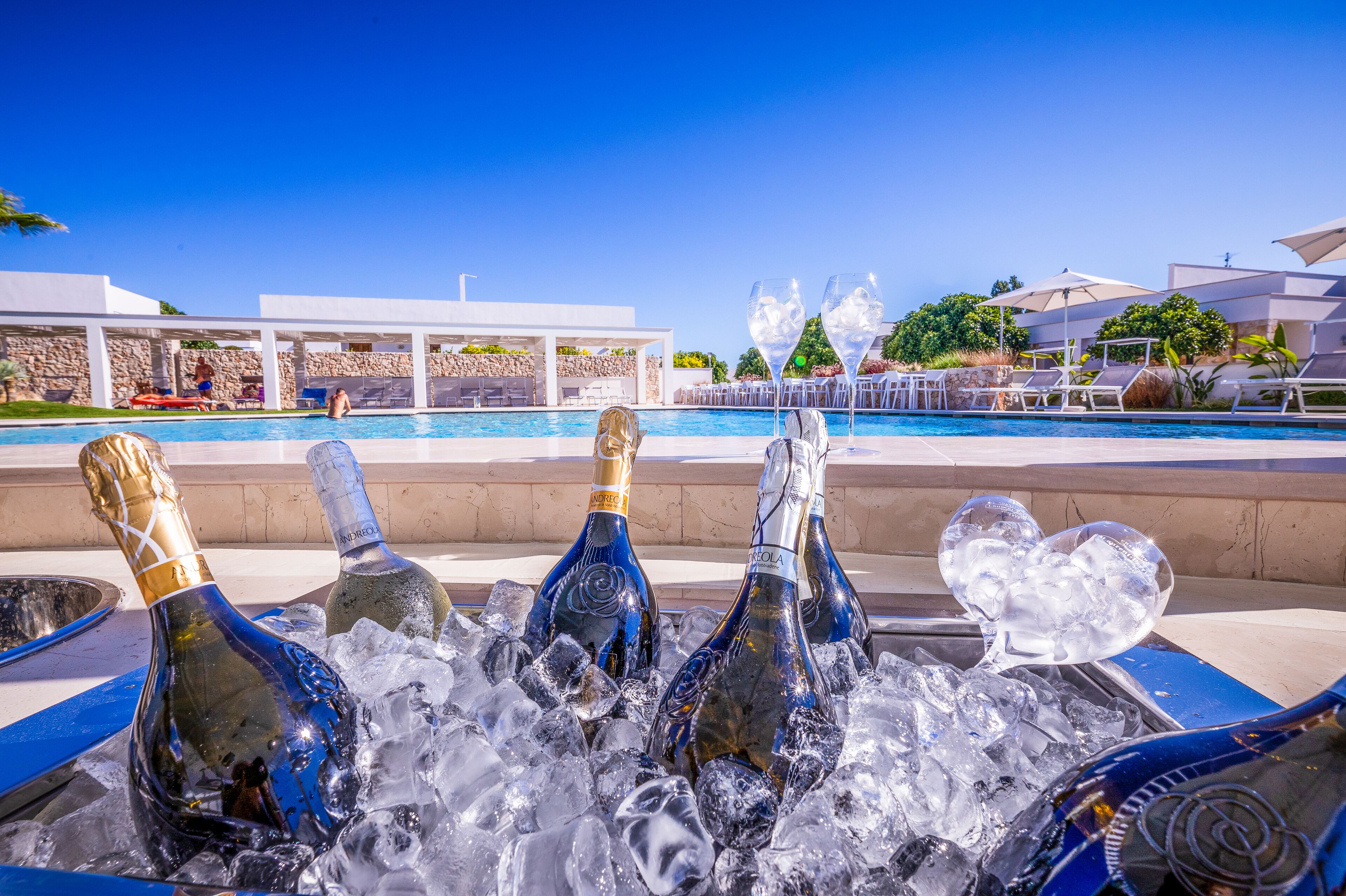 A poolside area with champagne bottles in ice, lounge chairs, and a clear view of the pool and resort buildings.