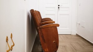 A hallway with a wooden chair leaning against the wall, a white door at the end, and a wooden floor. - Palazzo Bevilacqua Napoli B&B (Naples)