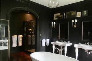 A black-themed bathroom with a freestanding bathtub, two sinks, and a glass-enclosed shower. - Inn at Kenmore Hall (Richmond)