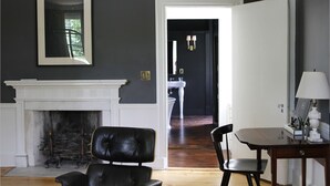 A room with a fireplace, a dining table, and a chair. There is a door leading to another room. - Inn at Kenmore Hall (Richmond)