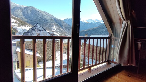 Habitación con balcón que da a un paisaje nevado de montaña.