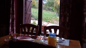 Una mesa de comedor con sillas, una botella de jugo y un vaso de agua.