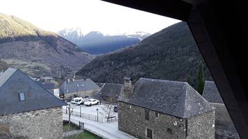 A view of a valley with stone buildings and a road with parked vehicles.