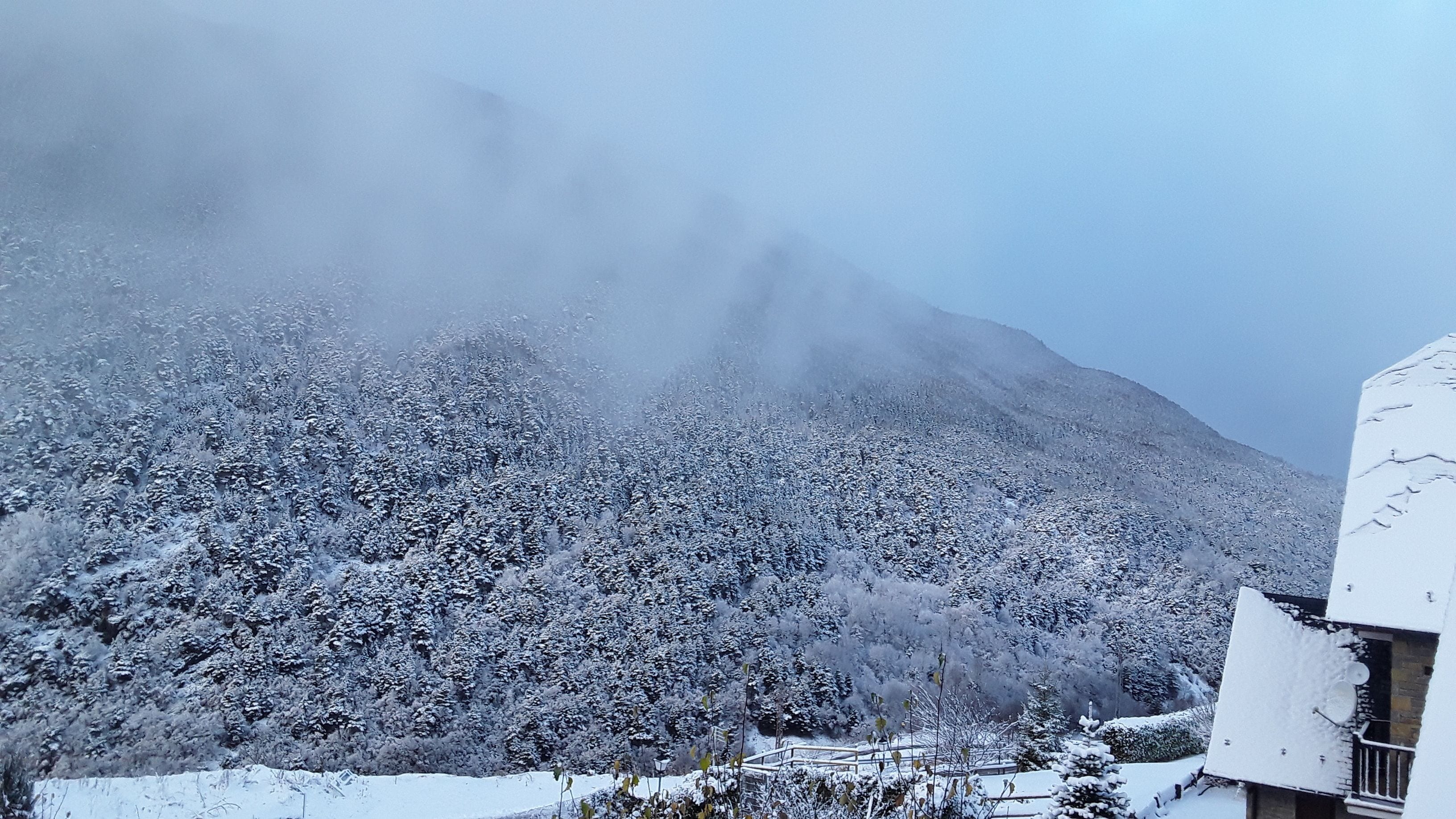 A snow-covered mountain with a building in the foreground.