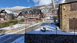 Un pueblo cubierto de nieve con casas de madera tradicionales, muros de piedra y una vista despejada de una montaña al fondo.