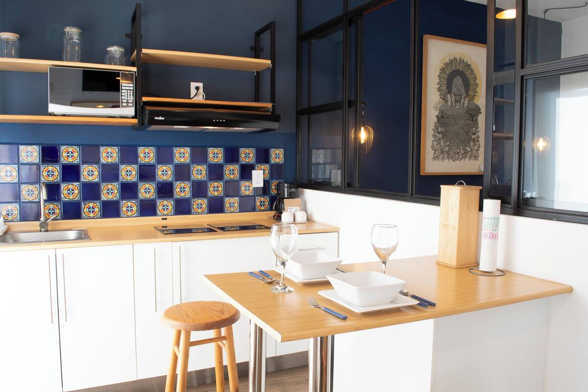 Una cocina moderna con encimera de madera, armarios blancos y salpicadero de azulejos.