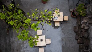 A rooftop terrace with a wooden table and chairs, surrounded by potted plants and a stone wall. - Romance City Hotel (Morelia)