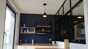 A compact kitchen with white cabinets, a microwave, a sink, and a wooden countertop. - Romance City Hotel (Morelia)