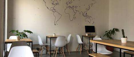 A modern workspace with a world map on the wall, multiple tables, chairs, and potted plants.