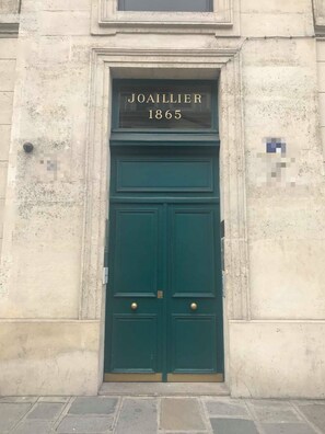 Una puerta doble verde con una placa que dice "JOAILLIER 1865" en la fachada de un edificio.