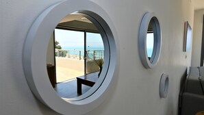 Un intérieur moderne doté de fenêtres rondes qui offrent une vue sur un balcon et la mer.
