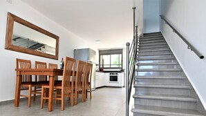 Une cuisine moderne avec un coin repas, un escalier et un grand miroir.