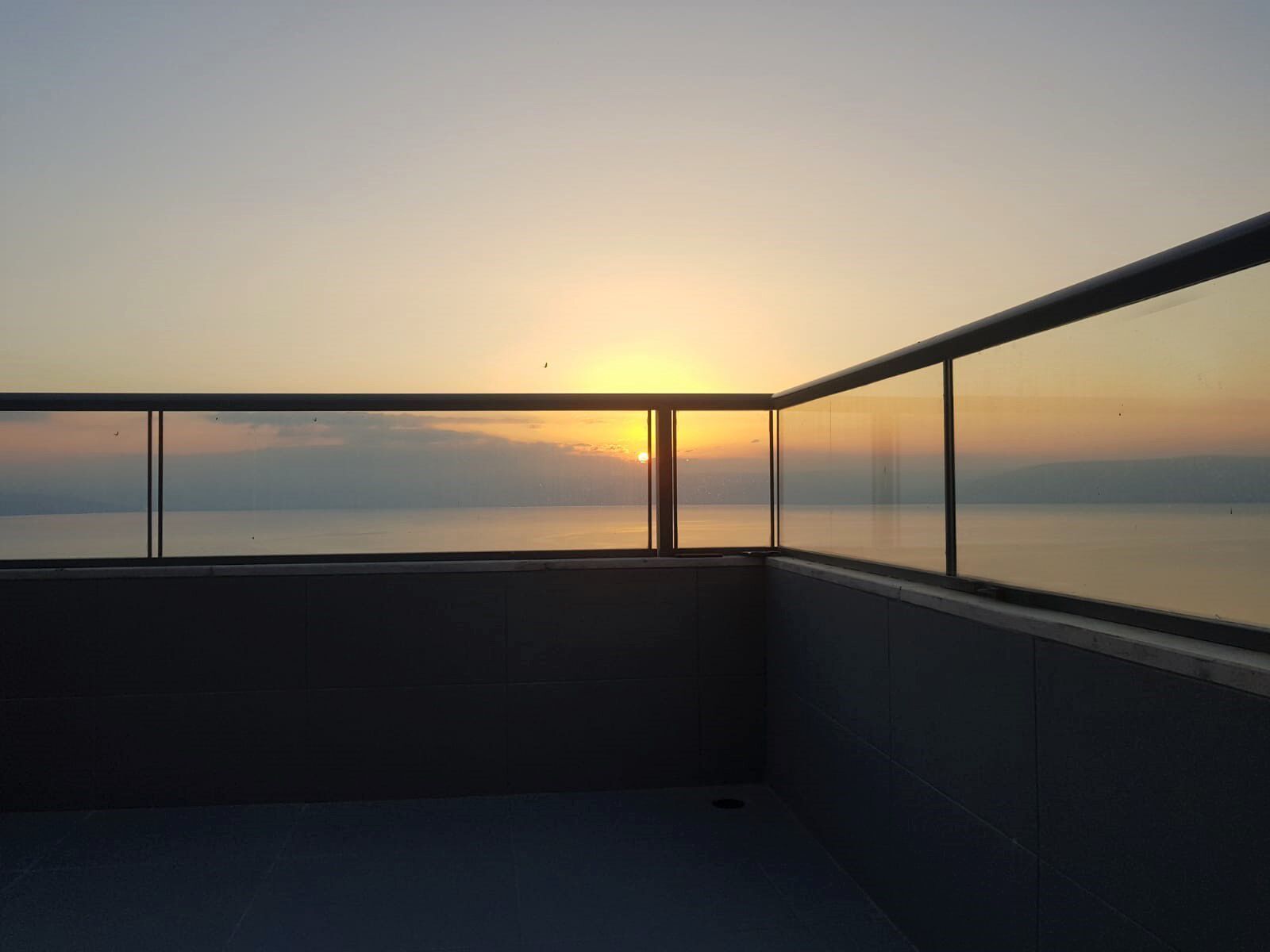 Un balcone con vista sul tramonto sull'acqua.