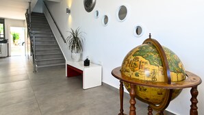 Un escalier menant à un palier où se trouvent un pot de fleurs et un globe terrestre posé sur un support.