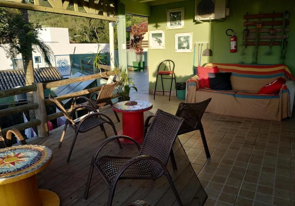 Un espacio al aire libre techado con sillas de mimbre, una mesa de mosaico y un sofá con cojines.