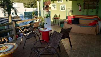 Un espacio al aire libre techado con sillas de mimbre, una mesa de mosaico y un sofá con cojines.