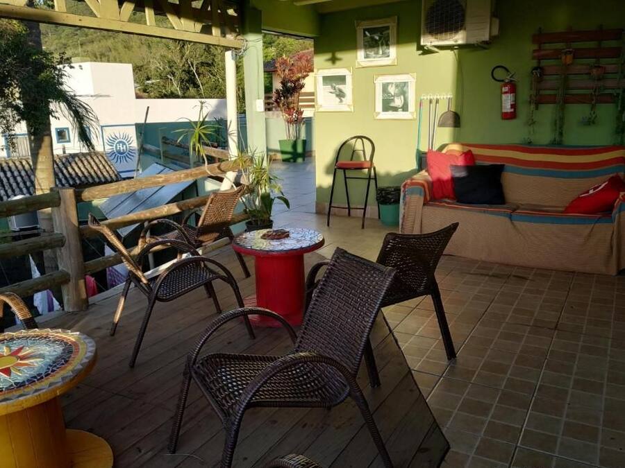 Un espacio al aire libre techado con sillas de mimbre, una mesa de mosaico y un sofá con cojines.