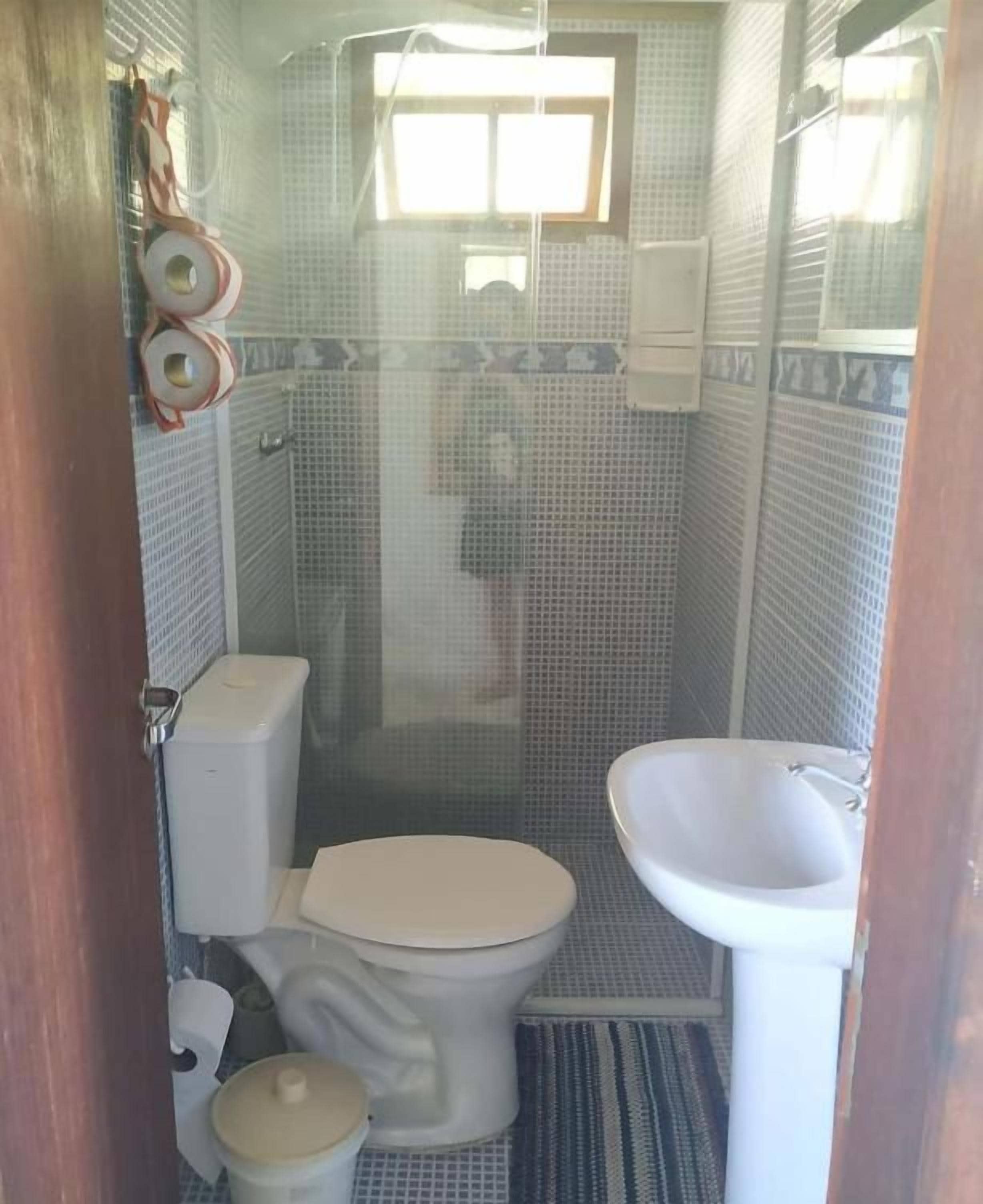 Un baño pequeño con inodoro, lavamanos y cabina de ducha.