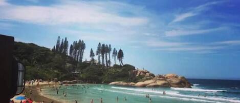A beach with umbrellas and people, and text indicating distance to Joaquina.