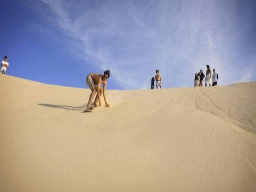 Paisagem arenosa com pessoas praticando atividades ao ar livre.