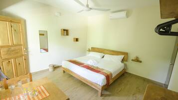 Ein Schlafzimmer mit einem hölzernen Bett, einem Deckenventilator, einem Holztisch mit Unterlage und einem Holzkasten.