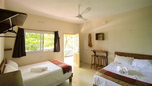 A room with two beds, a ceiling fan, a window with curtains, a small table, and a guitar on the wall. - Casa Almendro (Tulum)