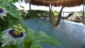 A thatched-roof structure with a hammock and a pool area. - Casa Almendro (Tulum)