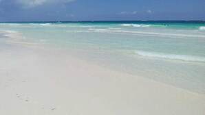 A beach with clear turquoise water and a wide sandy shore. - Casa Almendro (Tulum)