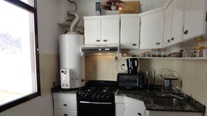 A compact kitchen with white cabinets, a stove, a toaster, and a sink. - Beautiful Quiet Apartment Near Aristides (Mendoza)